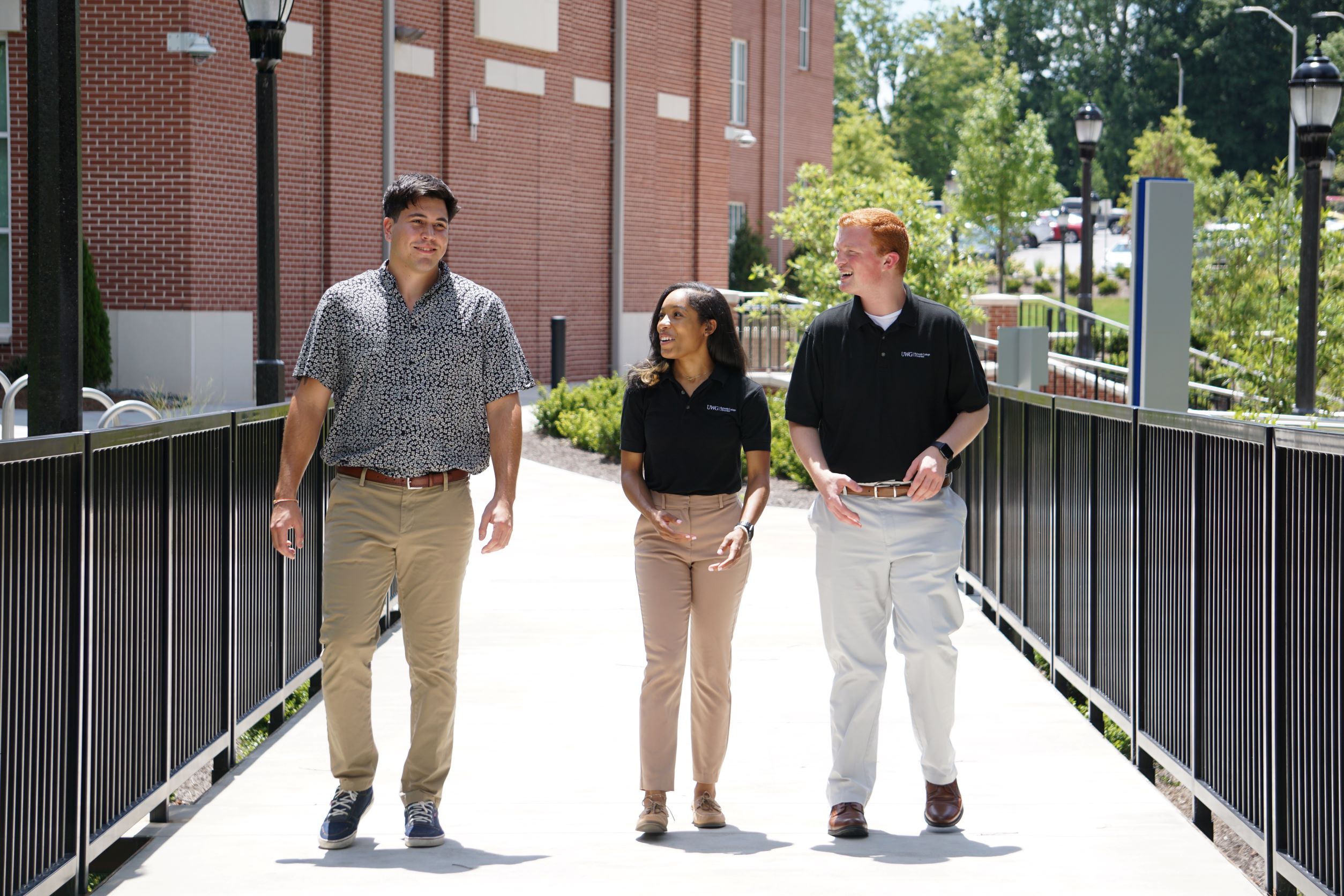 Three business students in professional dress walking across the bridge outside of the College of Business.