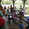 Group of people sitting at picnic tables under a pavilion.