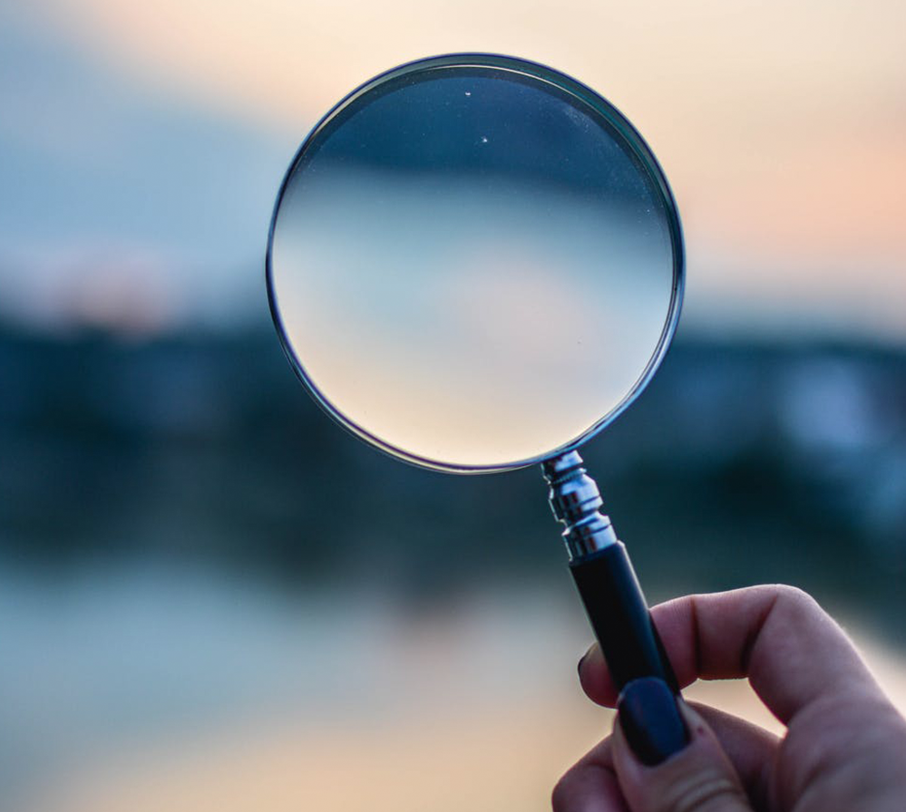 Hand holding a magnifying glass