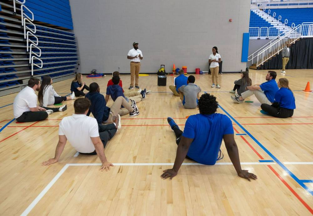 PE students in the gym listening to a speaker