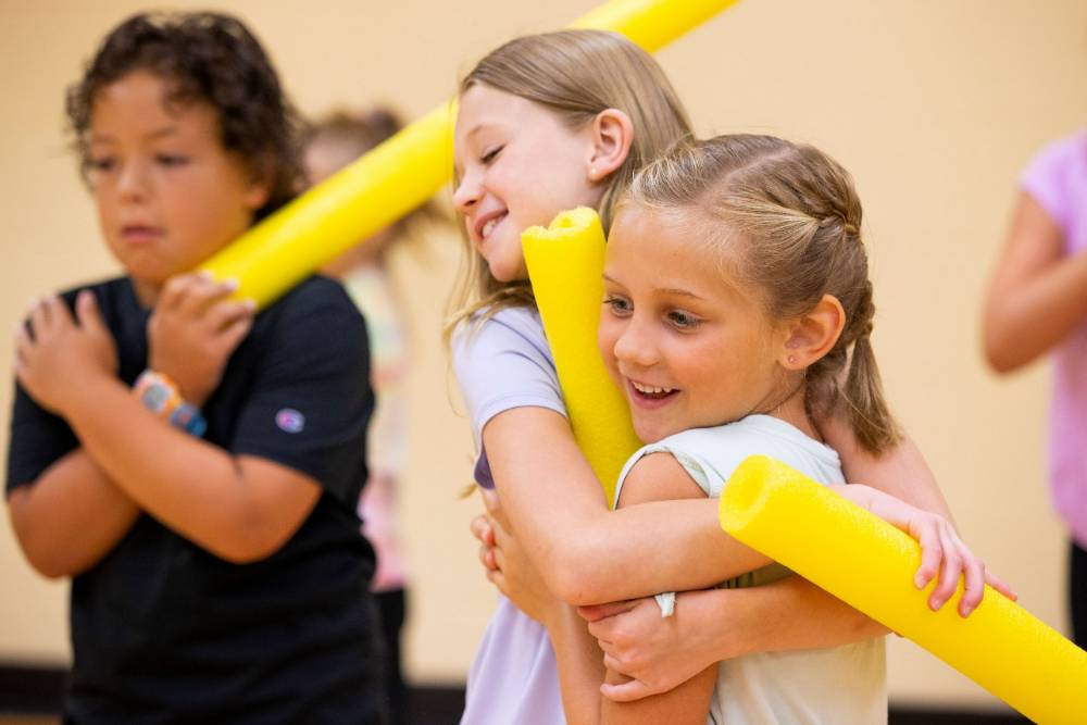 children in pe participating in a pool noodle activity
