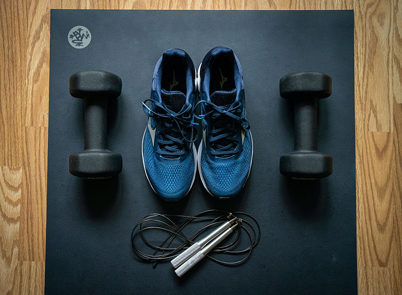 shoes, weights, and a jump rope on a yoga mat