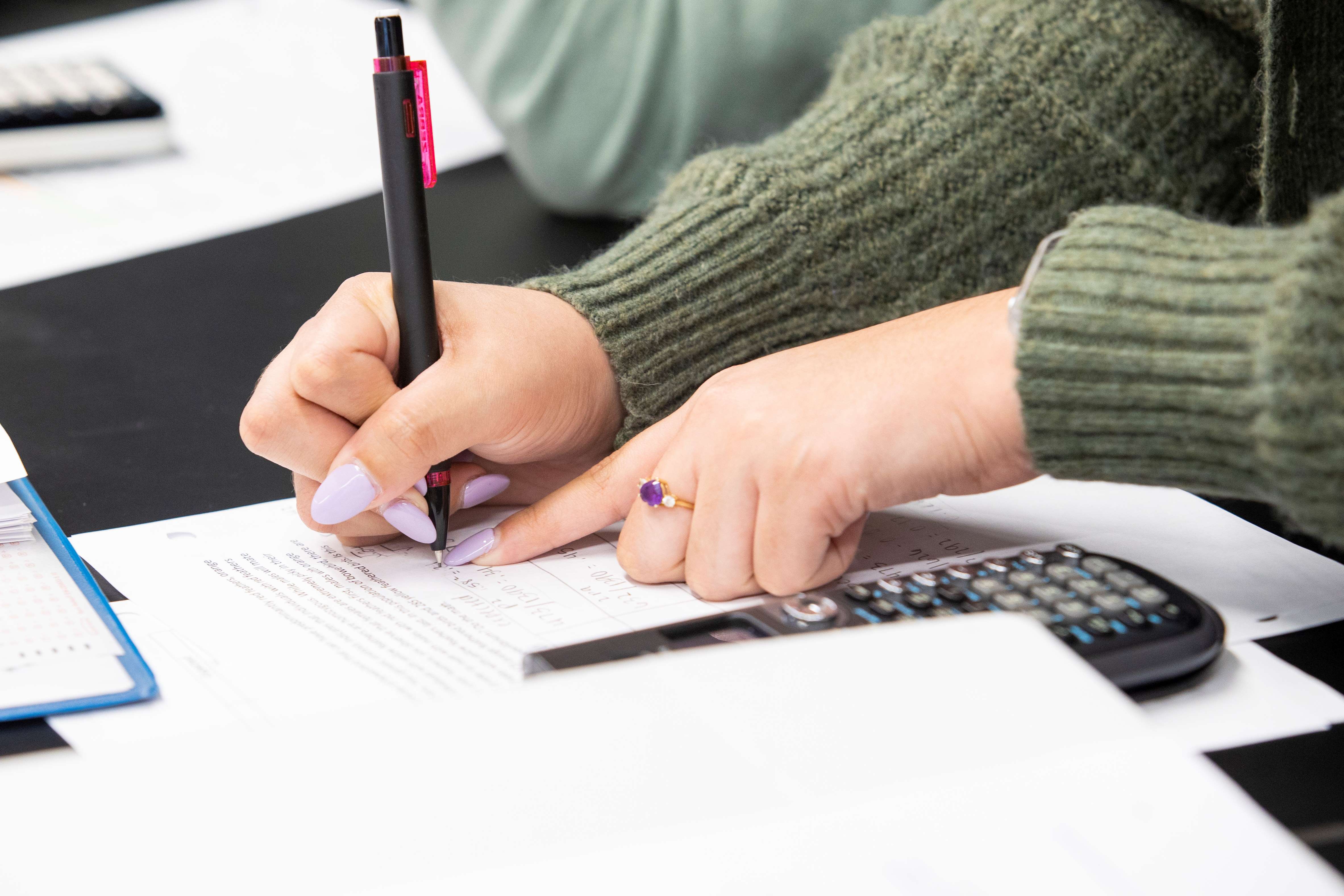 Girl completing calculations with a calculator.