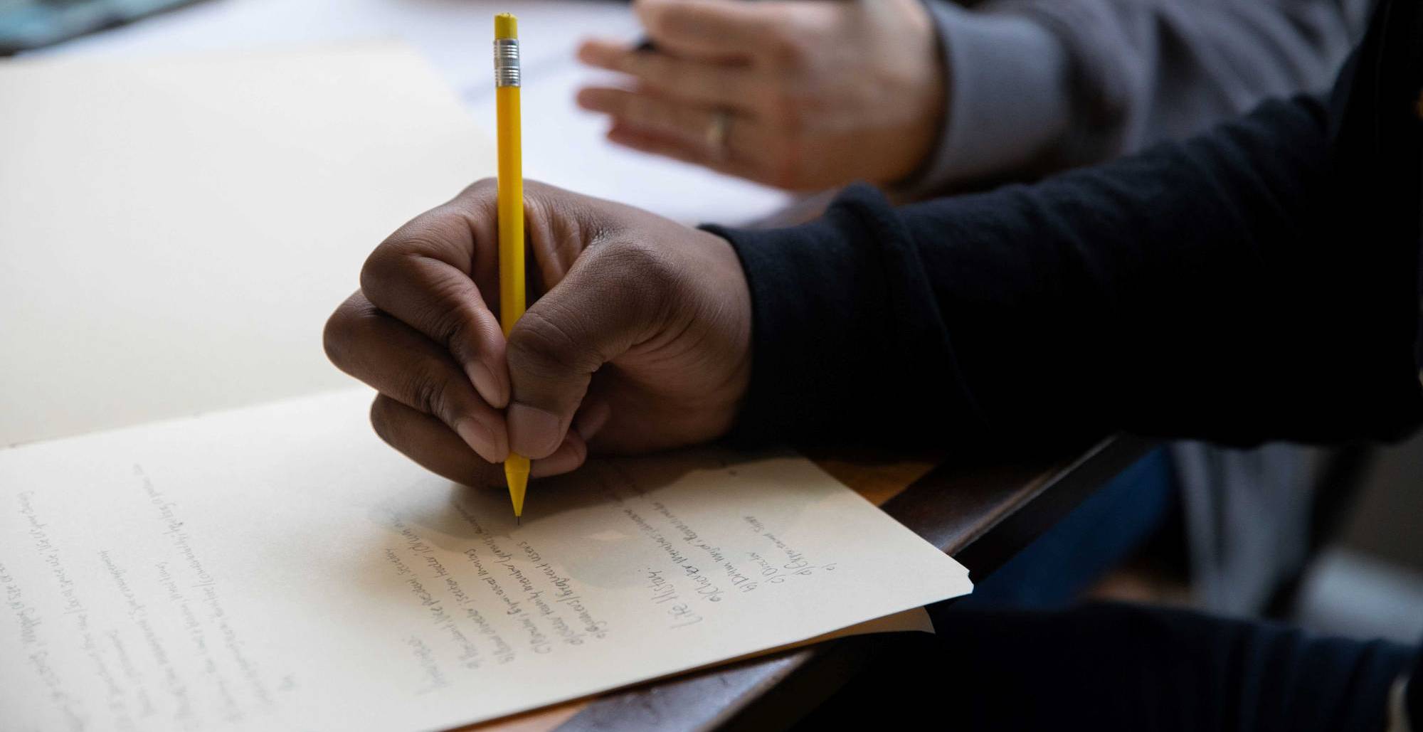 A hand writing with a pencil