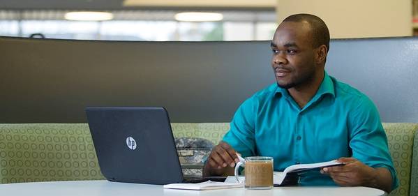 Guy in a library on a laptop.