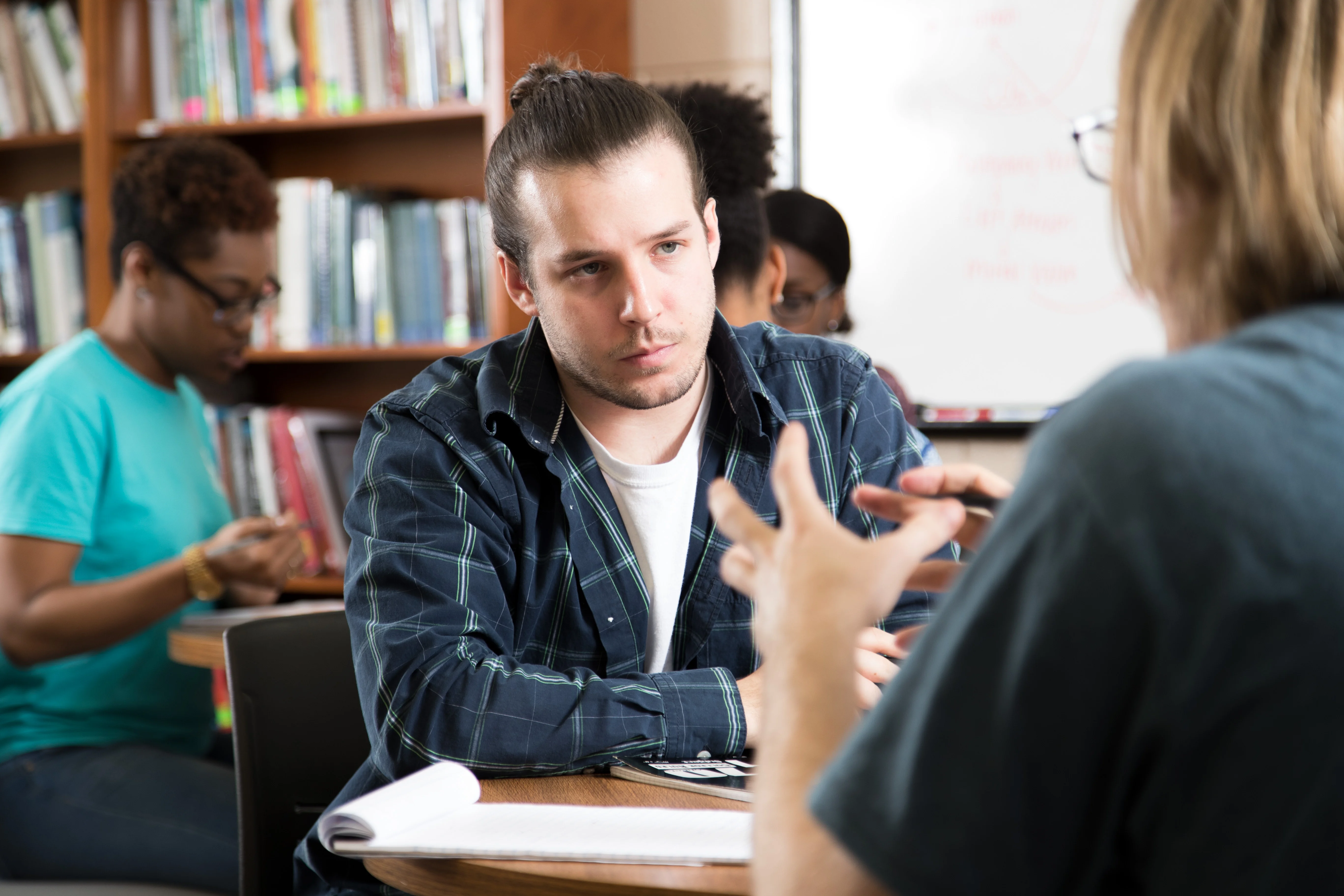 student sitting at a table talking with a faculty/staff memeber.