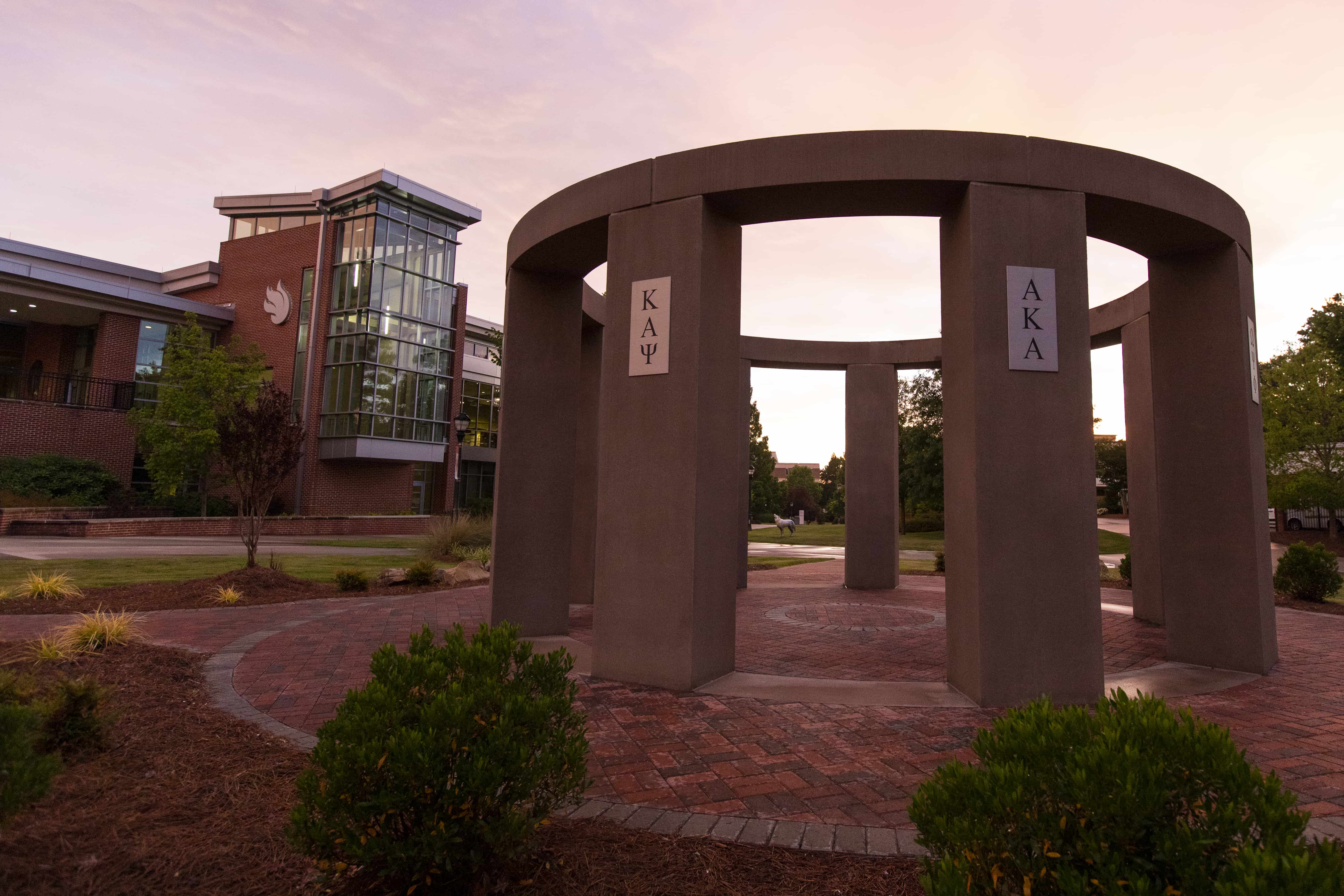 NPHC stone structure sitting in a garden area outside of East Commons dining hall.