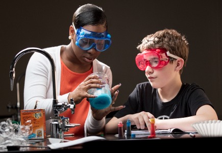 A student teaching a child in science lesson