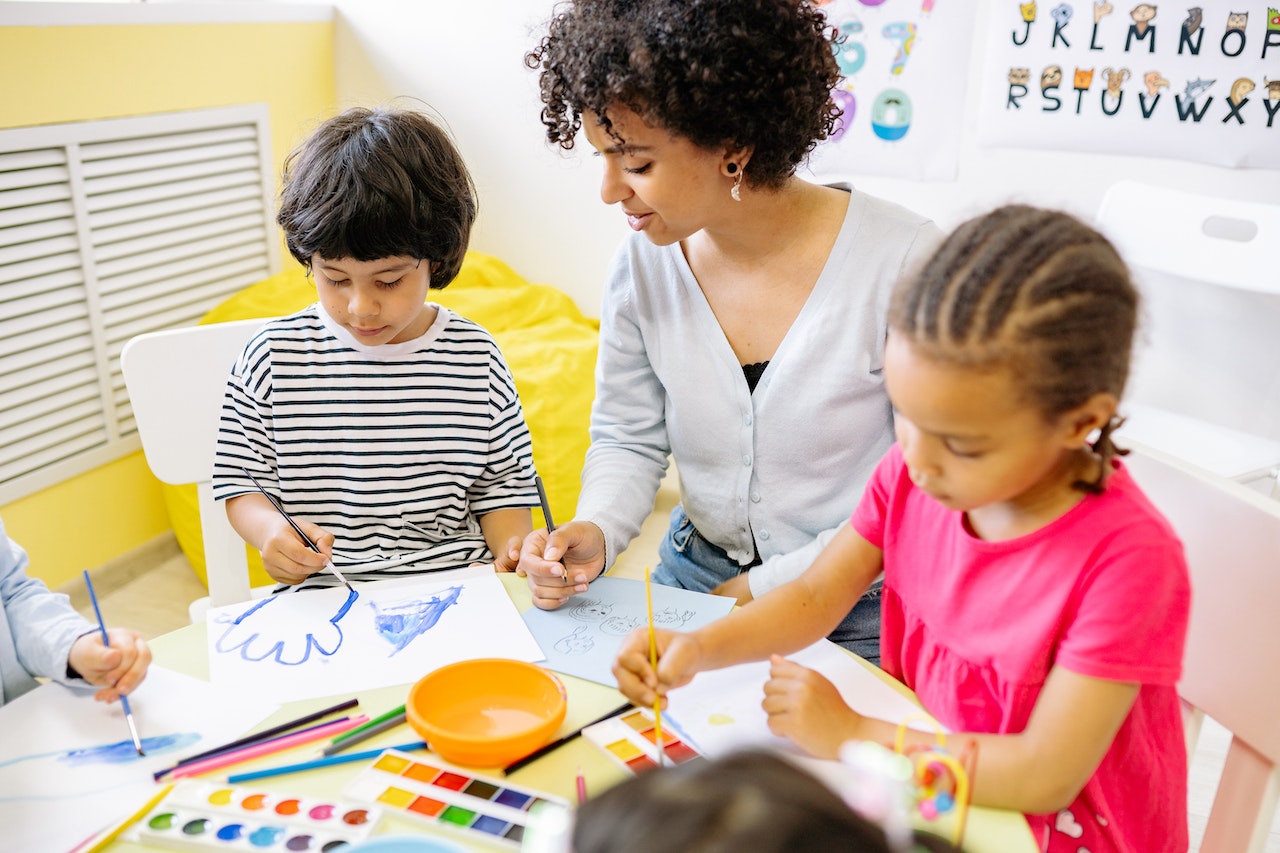 Teaching helping two children with art