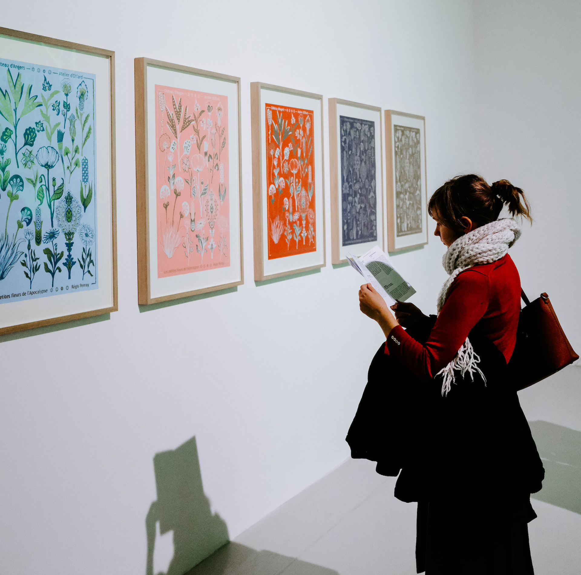 A woman standing in front of a series of four paintings of flowers