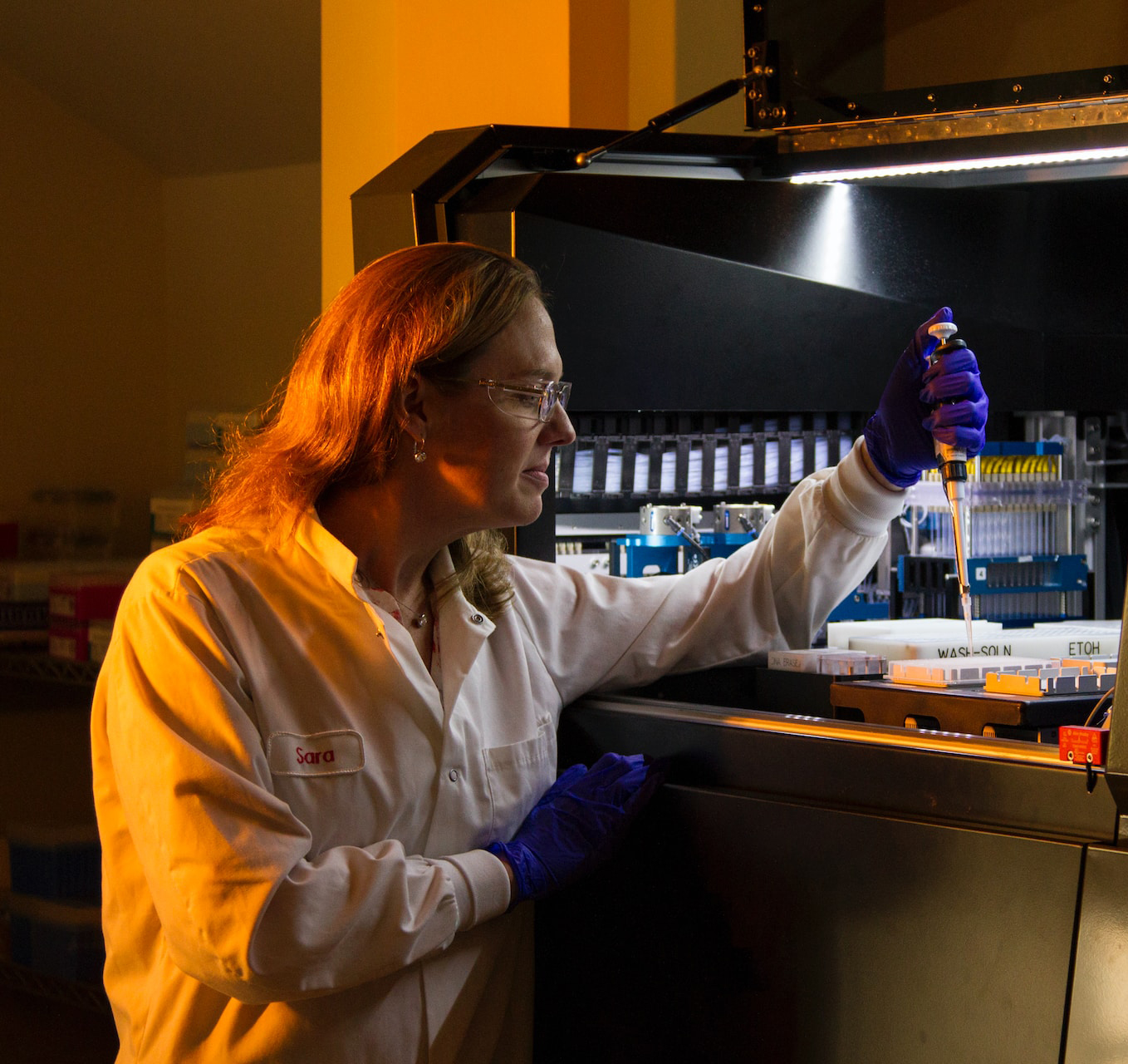 DNA Genotyping and Sequencing. Technician loads robot for genetic studies of the human papillomavirus (HPV) at the Cancer Genomics Research Laboratory