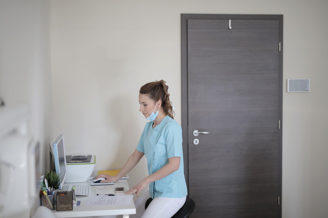 Woman in scrubs in front of a computer
