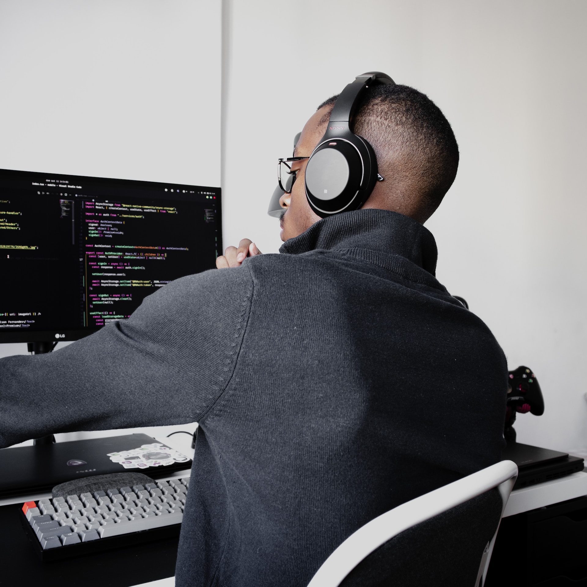 A black man with headphones sitting in front of a computer