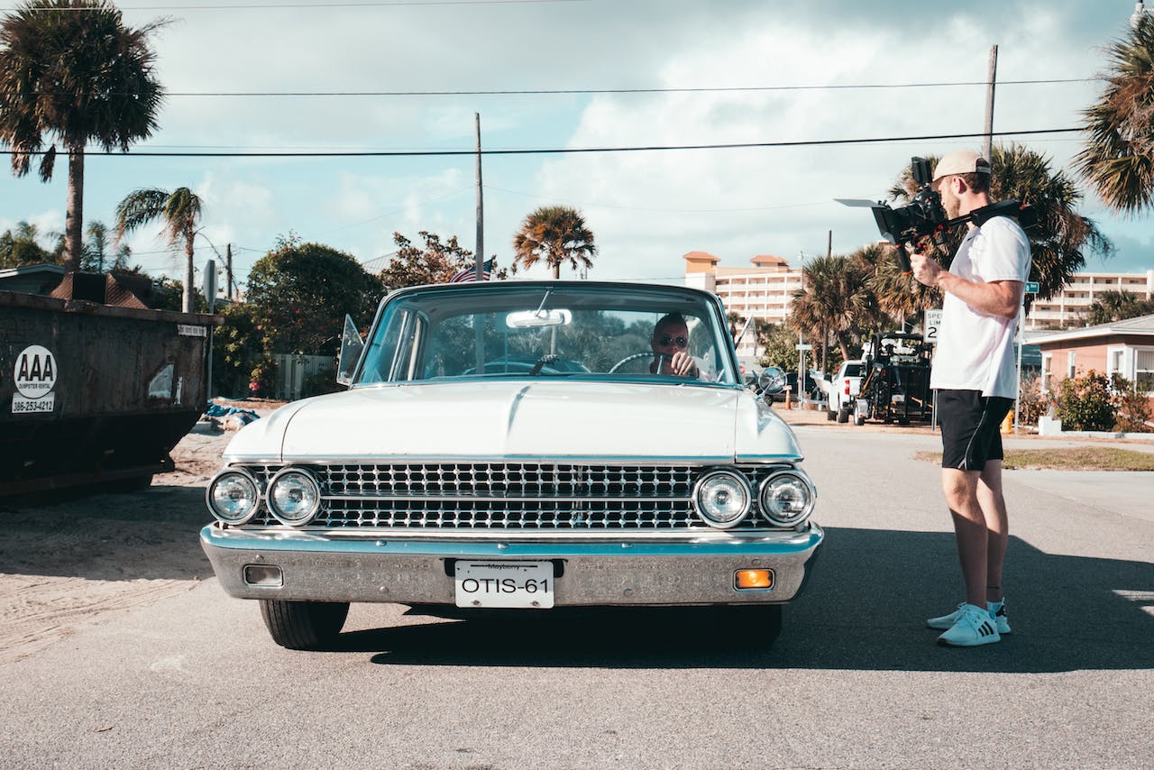 Man filming a person in a classic car