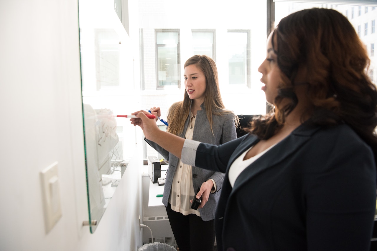 Two women writing on a white board