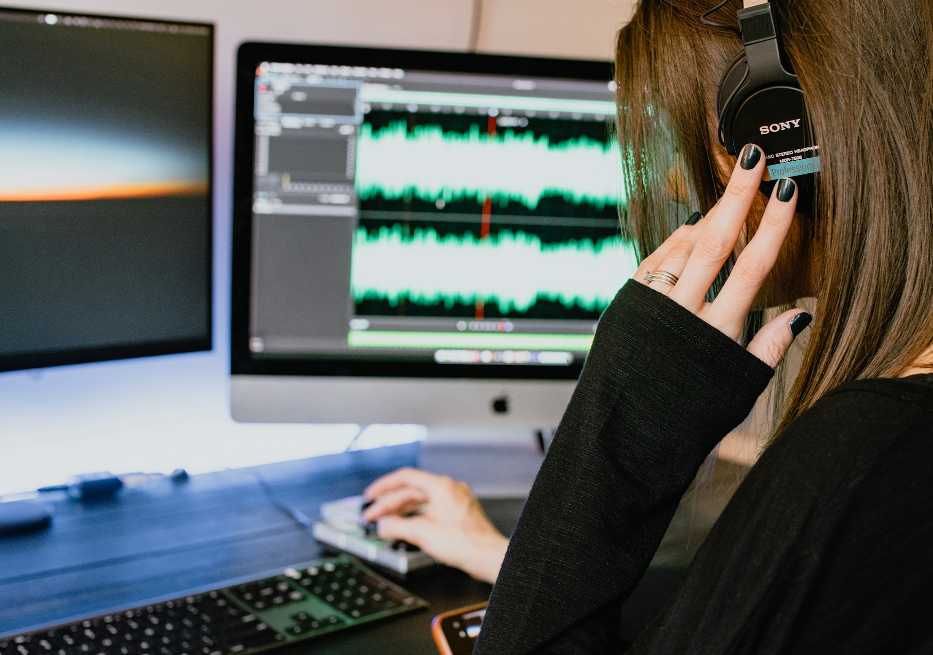 Woman with headphones working on music on a computer