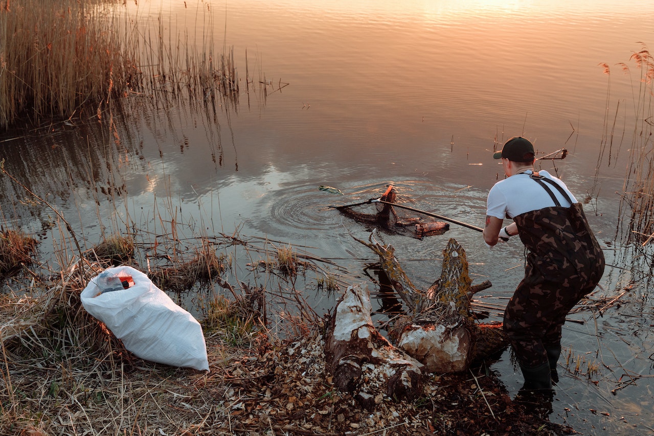 Man cleaning trash from a lake