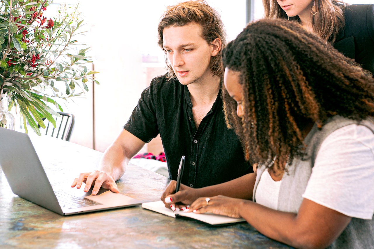 MAn on a computer with a woman taking notes