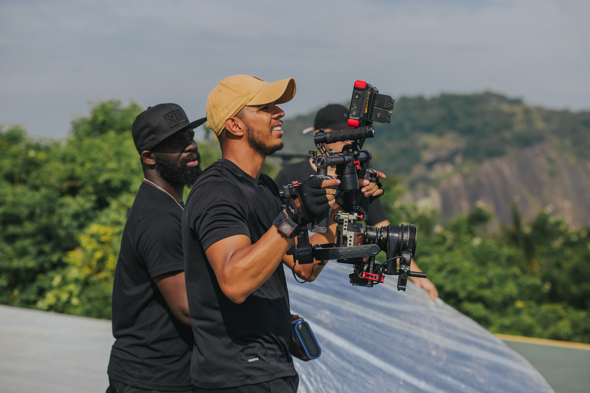 man in black t-shirt and brown hat holding black dslr camera