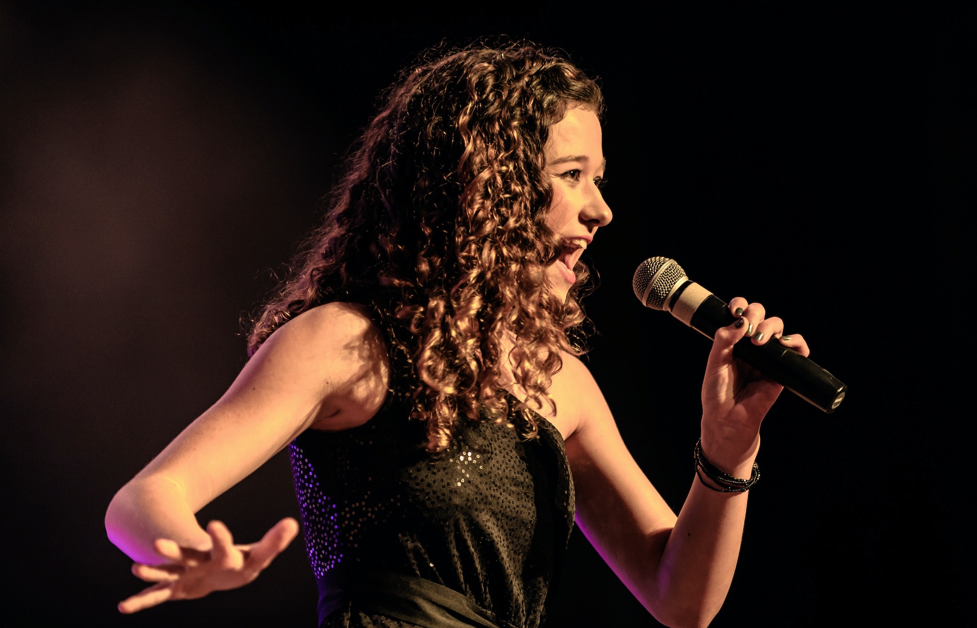 A woman singing on stage dressed in a black dress