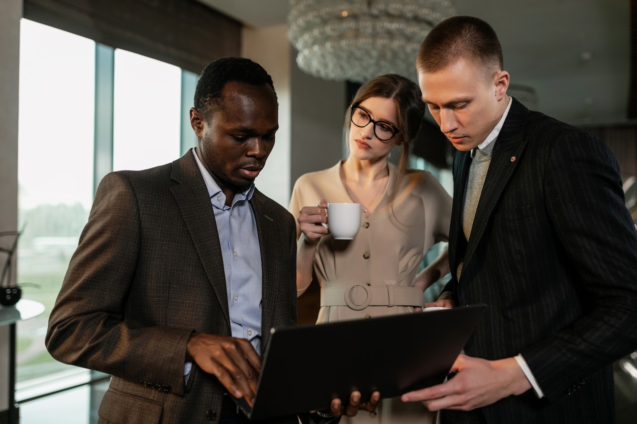 Three people talking around a laptop