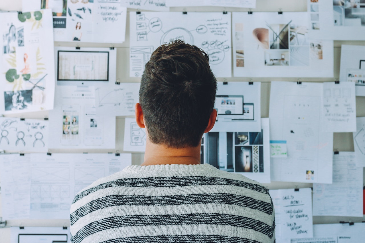 Man standing in front of a board full of various printouts