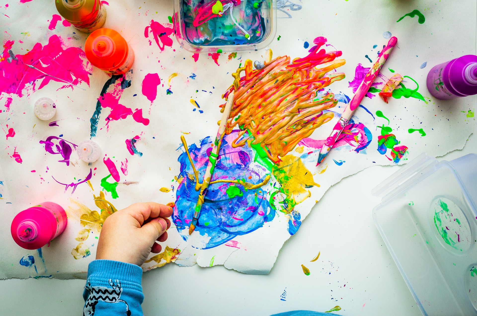 Child painting. Paint is everywhere on the table as well as the paper