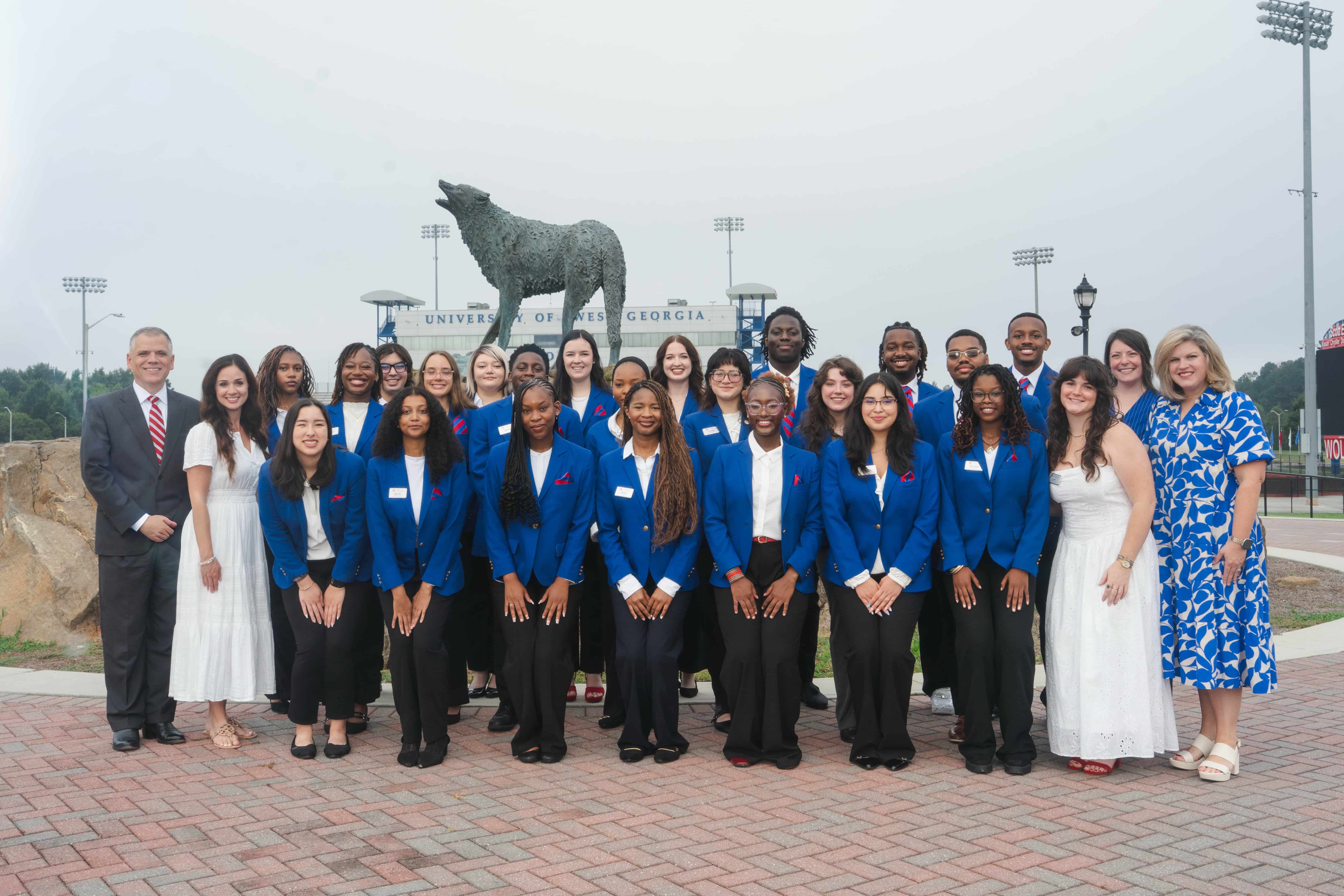 Blue Coats 2026 group photo at Wolf Plaza in front of the wolf statue.