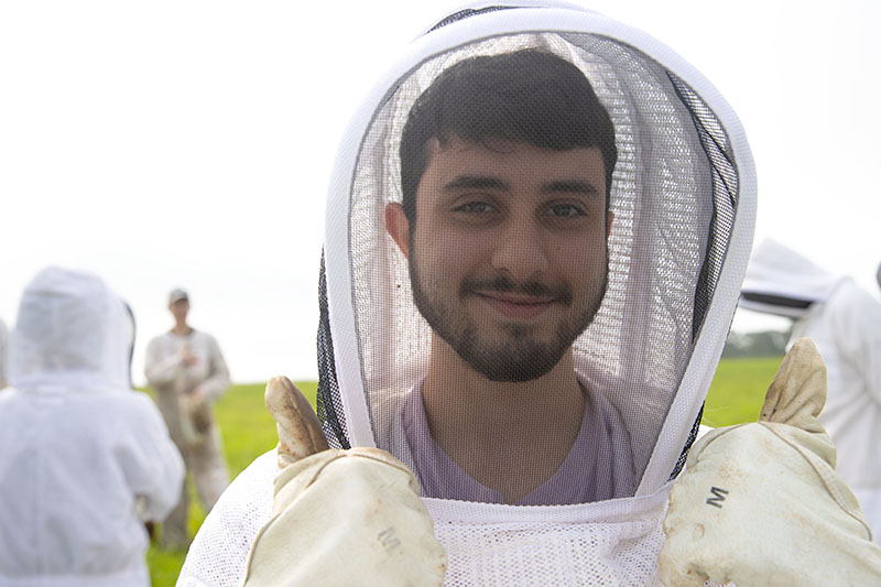 male student with beekeeping protective hear on