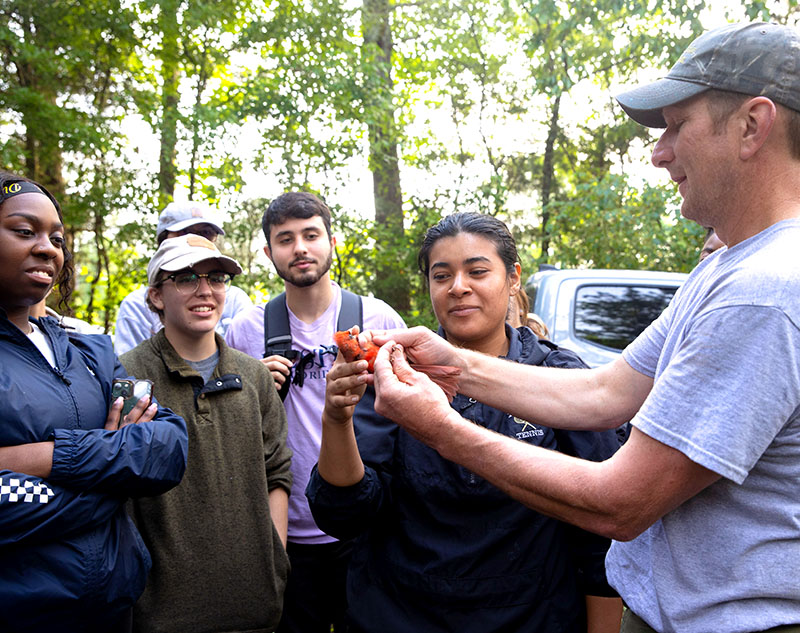 students looking at cardinal being handled