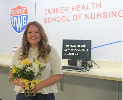 Picture of Student with flowers in front of computer sign