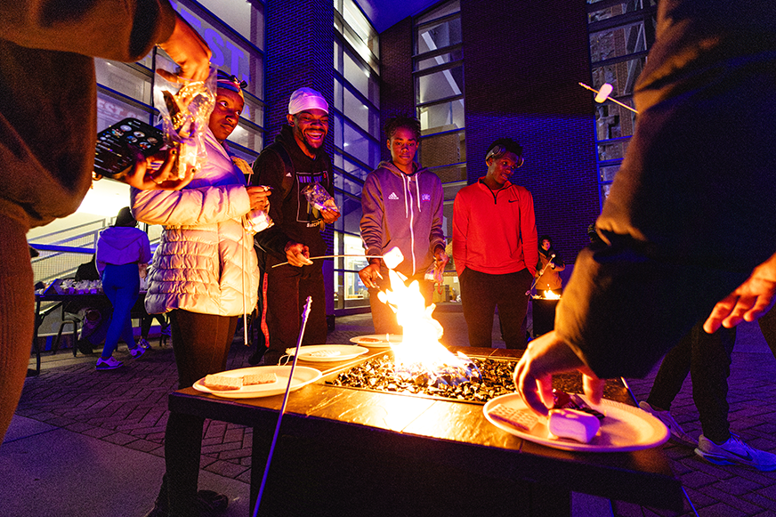 Students making s'mores on campus center back patio