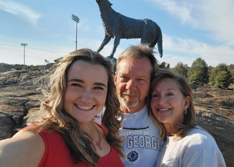 student with parents by wolf statue