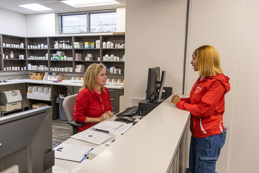 Student at pharmacy window talking to pharmacist