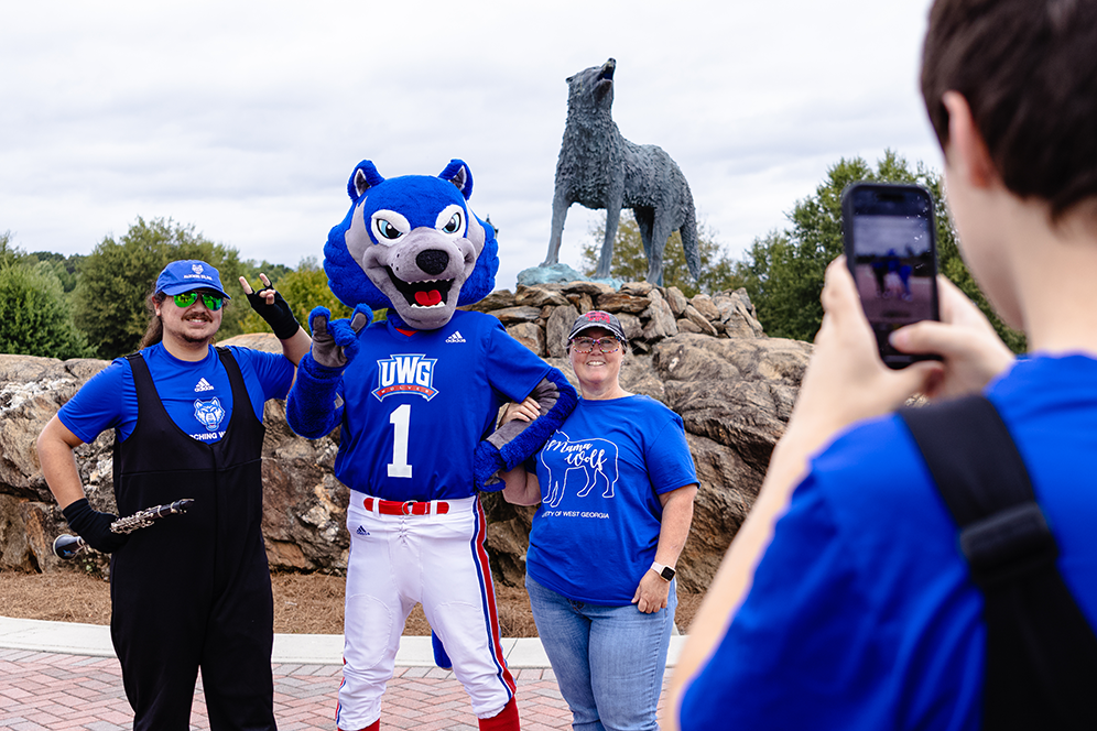 Student and mom with wolfie taking pic by wolf statue