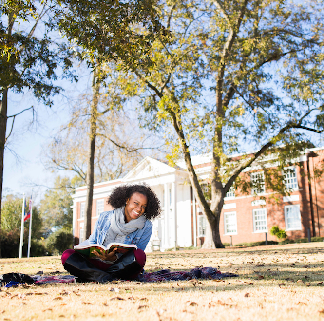 female student sitting outside in front of Adamson Hall