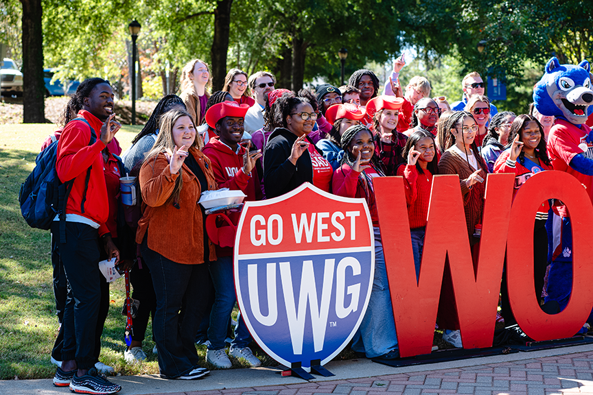 students behind wolves red sign with wolves hand gesture
