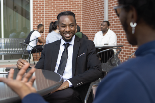 Student in a suit talking to another student