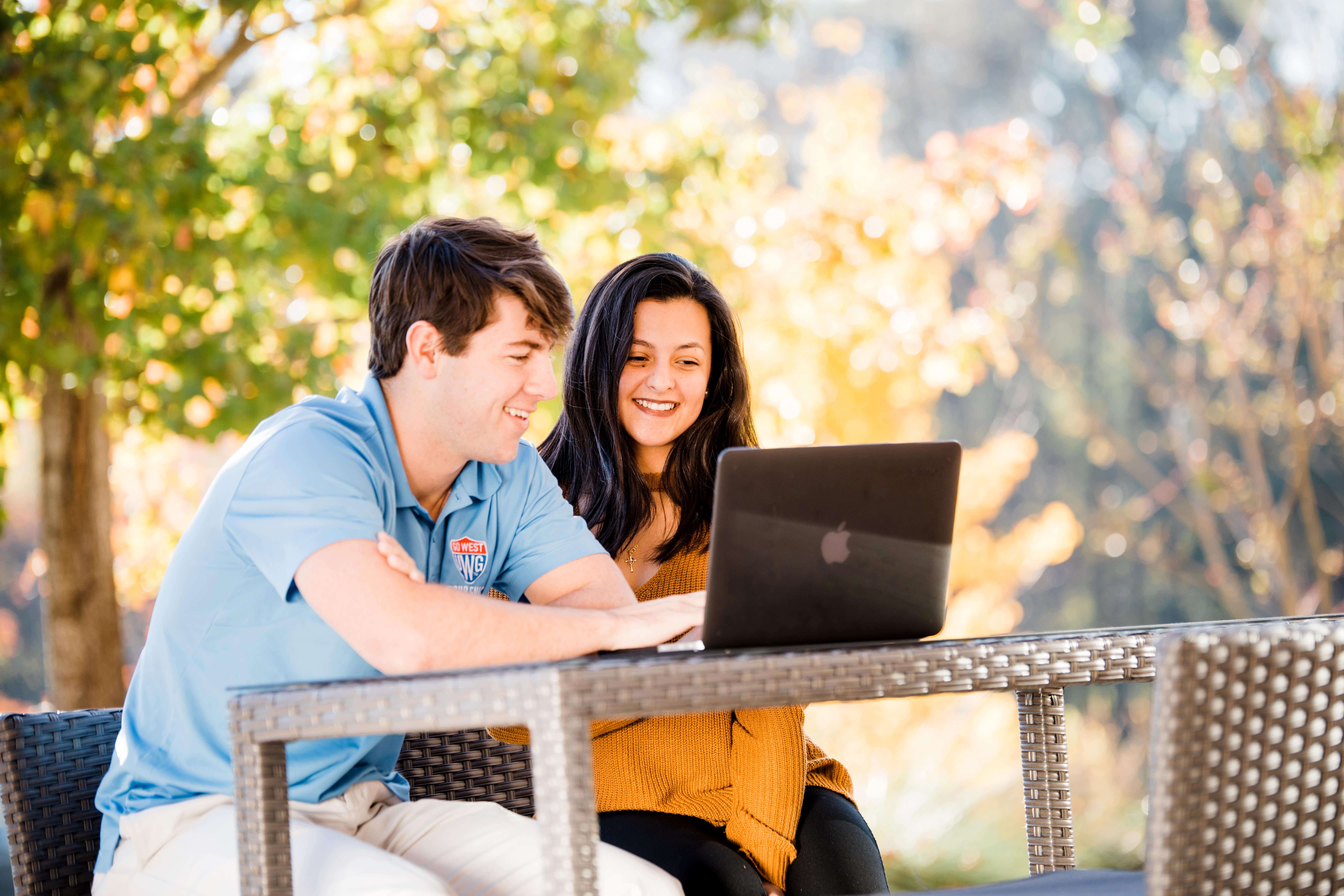 Students sitting at an outside table studying.