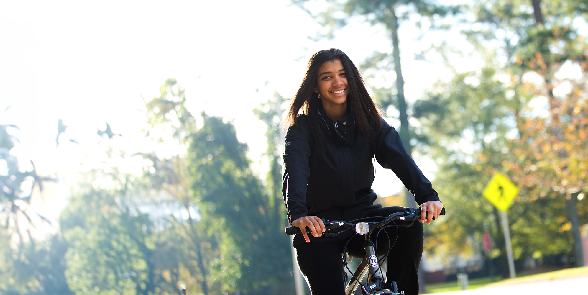 Woman riding her bike on campus smiling.