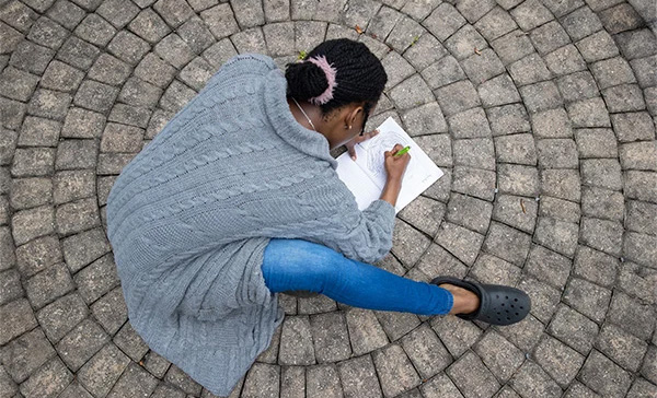back of student drawing on paper against circular paving stones