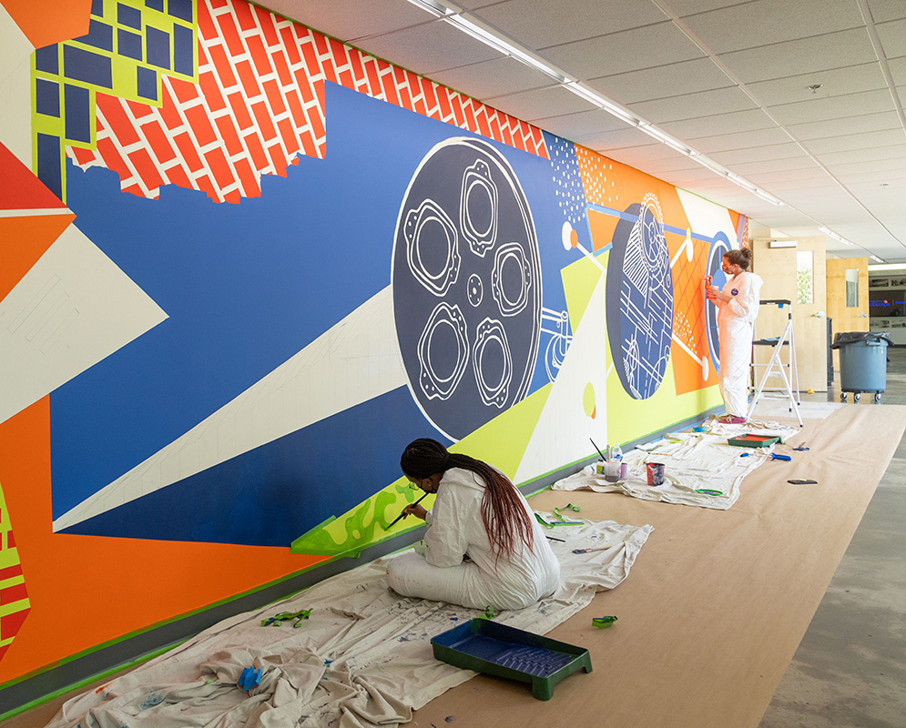Art students painting a mural at the Newnan campus.
