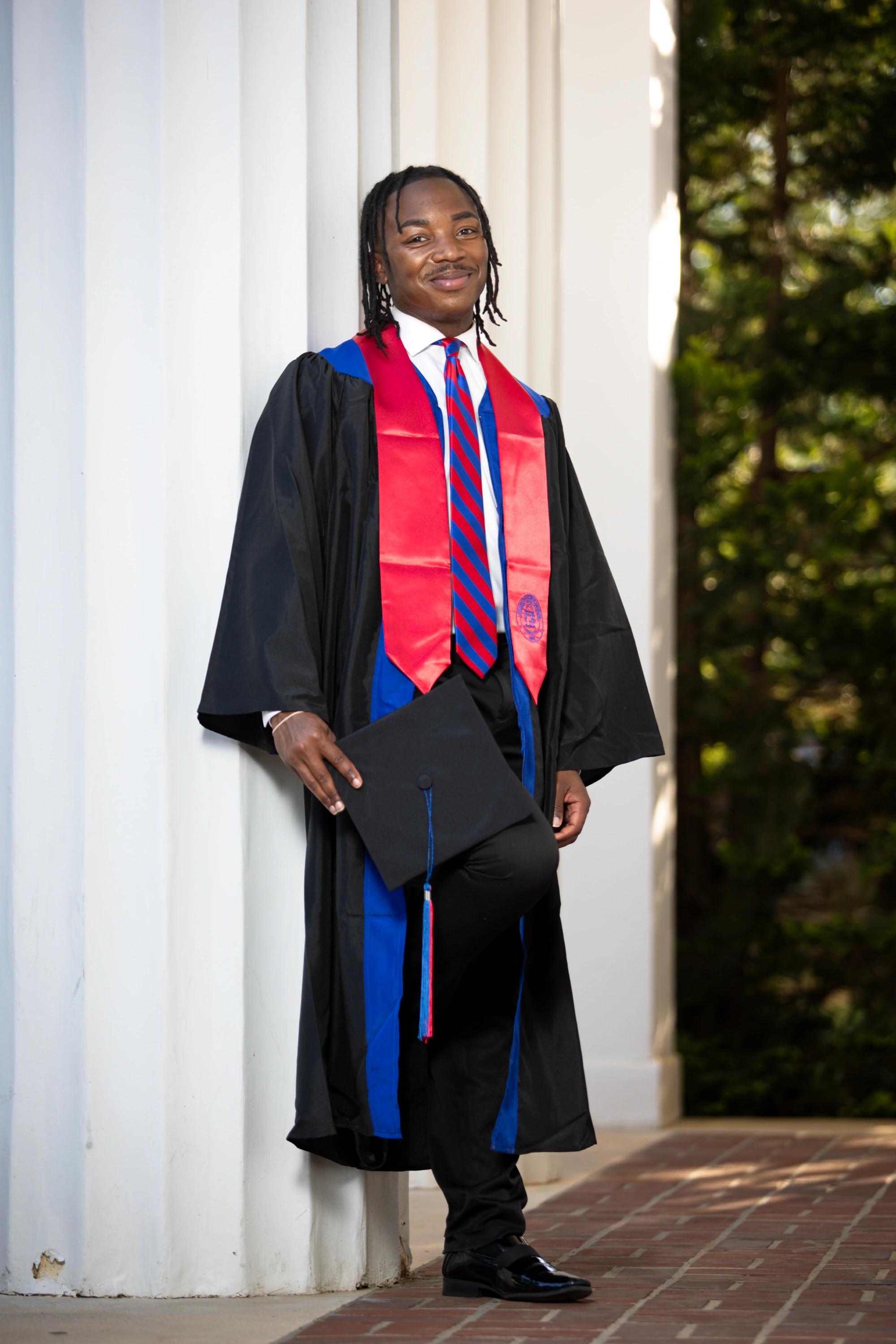 Tristain dressed in cap and gown standing outside the old auditorium.