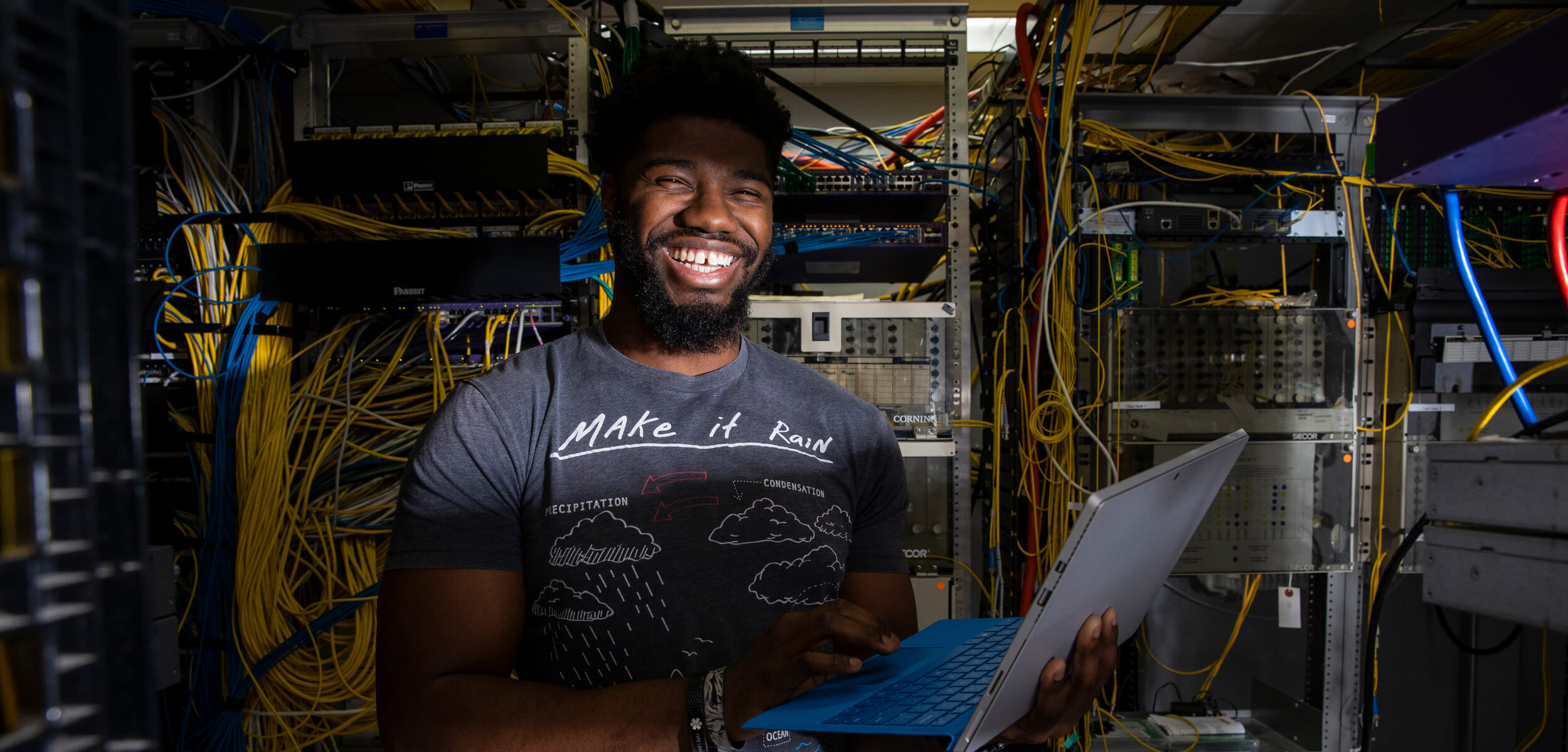 Student standing in server room smiling.