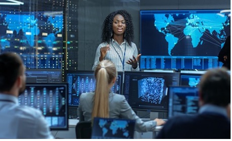 Woman in business attire standing presenting to her team.