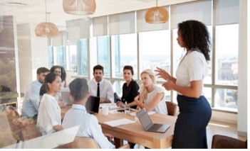 Teaching standing in front of a table of students talking.