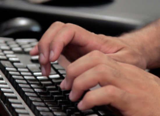 Hands typing on a laptop