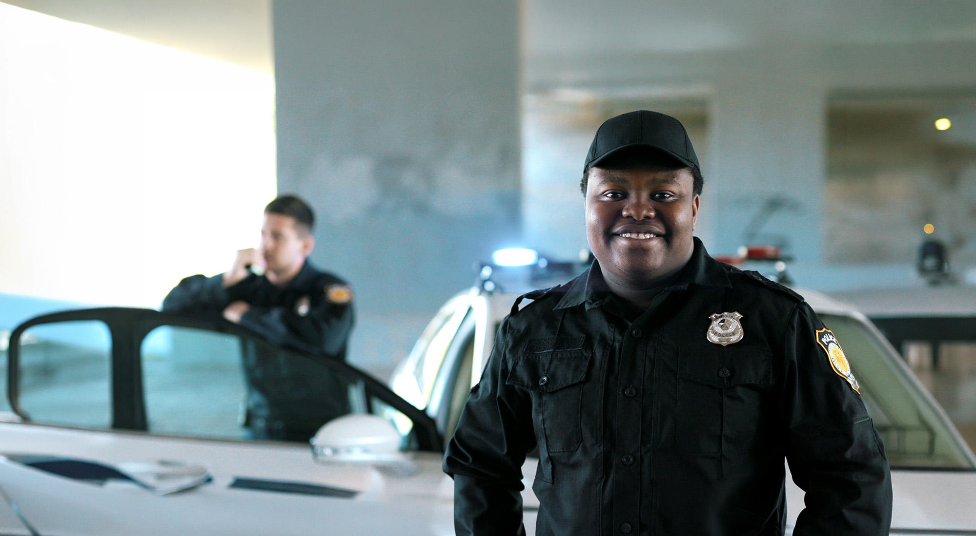 police officers outside by patrol car, one facing the camera and smiling