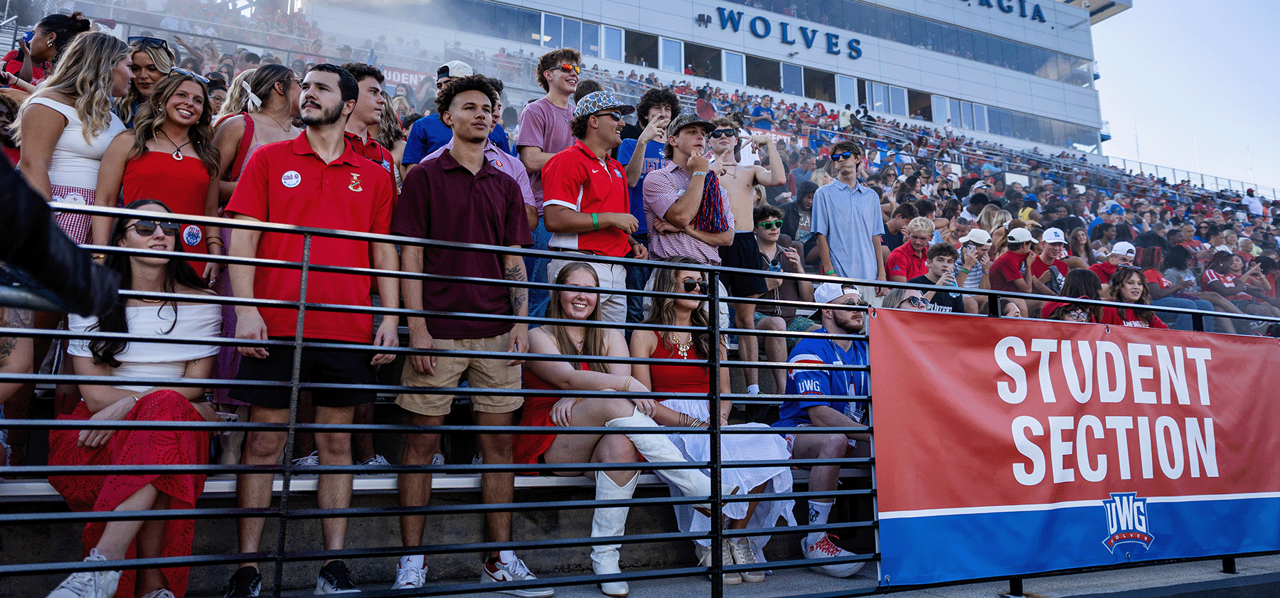 Greek students in student section at University stadium wearing blue and red outfits cheering on UWG football