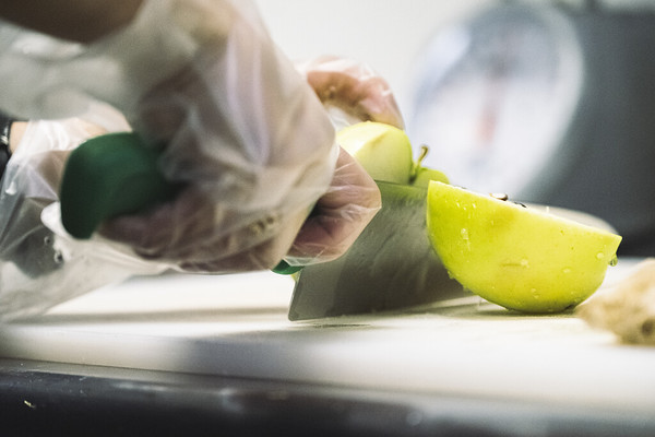 Chef cutting a green apple on a cutting board.